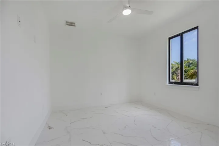 Empty room with baseboards, marble finish flooring, and a ceiling fan