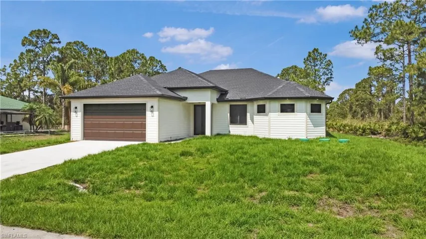 View of front facade featuring a garage, concrete driveway, a front yard, and roof with shingles