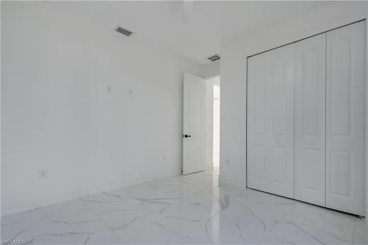 Unfurnished bedroom featuring light marble finish flooring, baseboards, a closet, and a ceiling fan