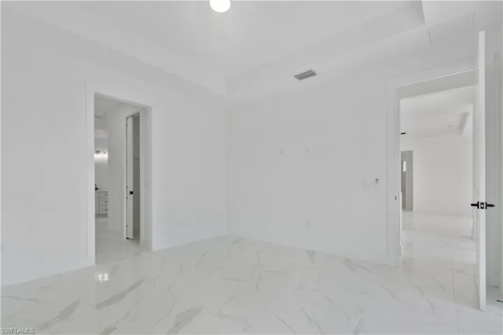 Empty room featuring marble look tiles and baseboards