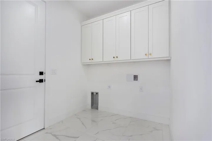 Washroom featuring cabinet space, marble look tile flooring, hookup for an electric dryer, baseboards, and washer hookup