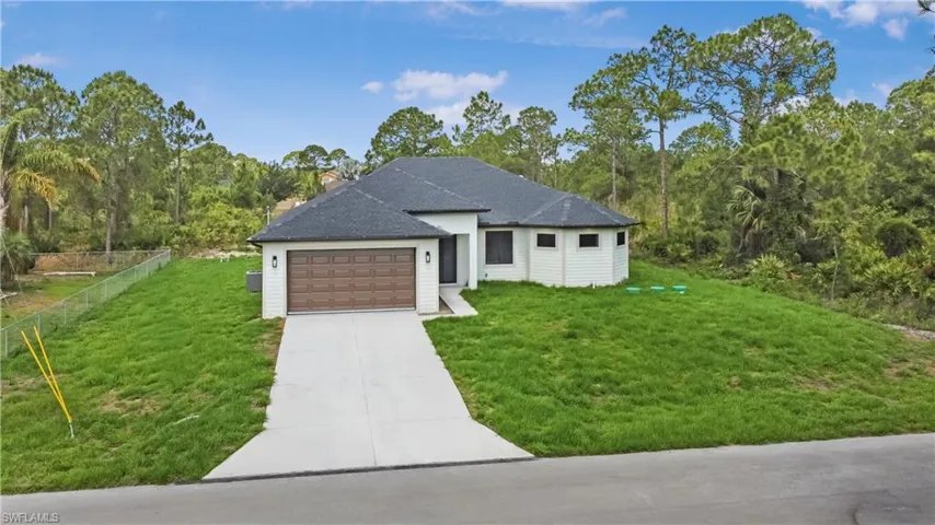 View of front facade with driveway, a garage, and a shingled roof