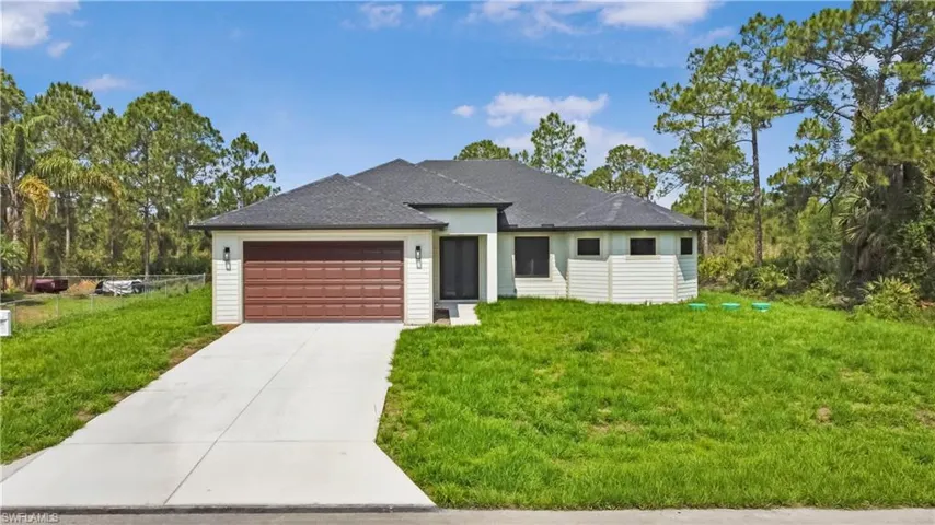 View of front of property with an attached garage, concrete driveway, a front lawn, and a shingled roof