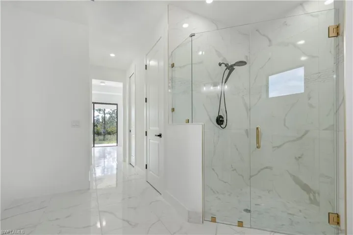 Bathroom featuring a marble finish shower, marble finish floors, baseboards, and recessed lighting