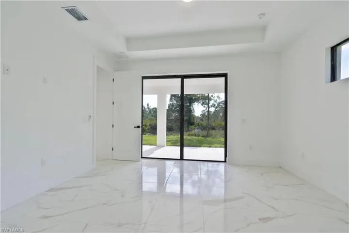 Empty room featuring marble finish flooring, baseboards, and a raised ceiling