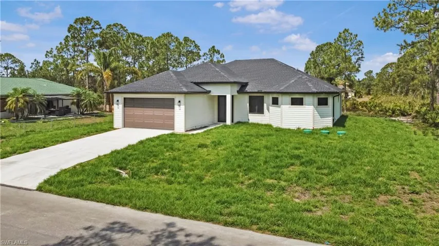 View of front facade featuring concrete driveway, an attached garage, and a front lawn