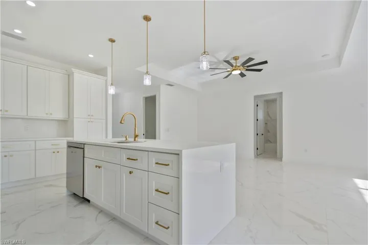 Kitchen with stainless steel dishwasher, a sink, recessed lighting, open floor plan, and light marble finish floors