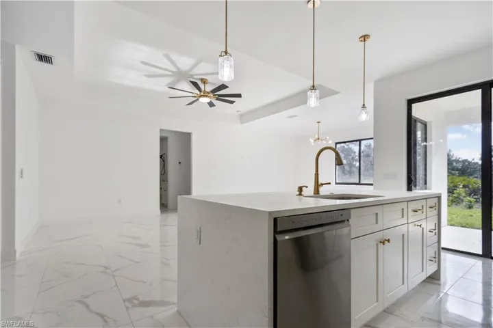 Kitchen with a sink, stainless steel dishwasher, open floor plan, a raised ceiling, and white cabinets