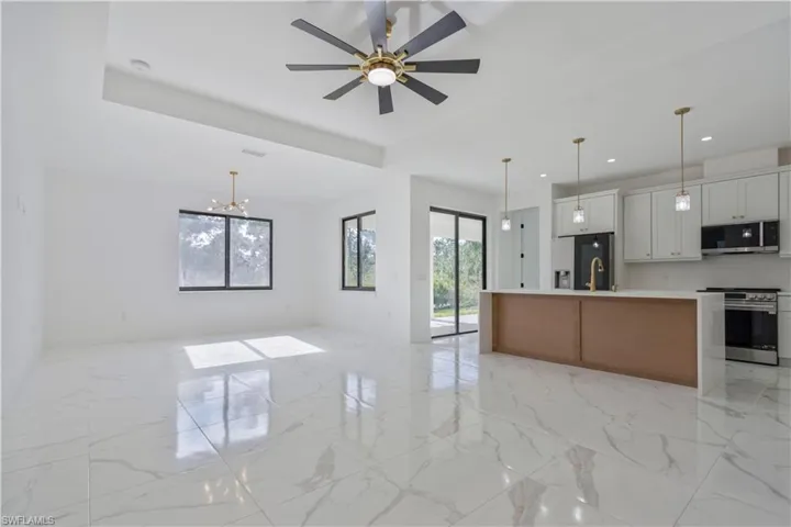 Kitchen featuring appliances with stainless steel finishes, open floor plan, light countertops, recessed lighting, and light marble finish flooring
