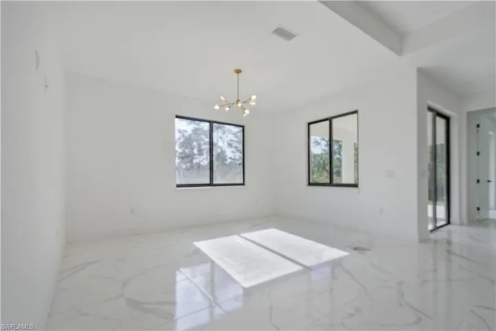 Unfurnished room with marble tiled floors and a chandelier