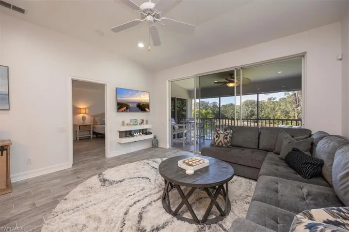 Living room featuring wood finished floors, ceiling fan, baseboards, lofted ceiling, and visible vents