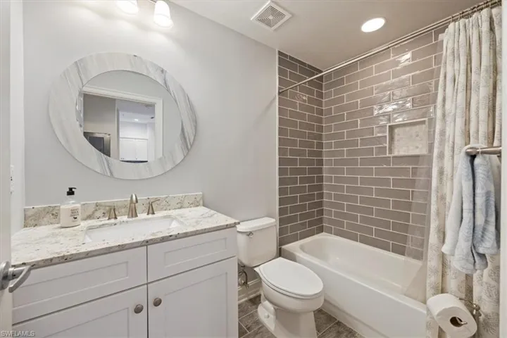 Full bath with vanity, shower / bath combination with curtain, toilet, visible vents, and recessed lighting