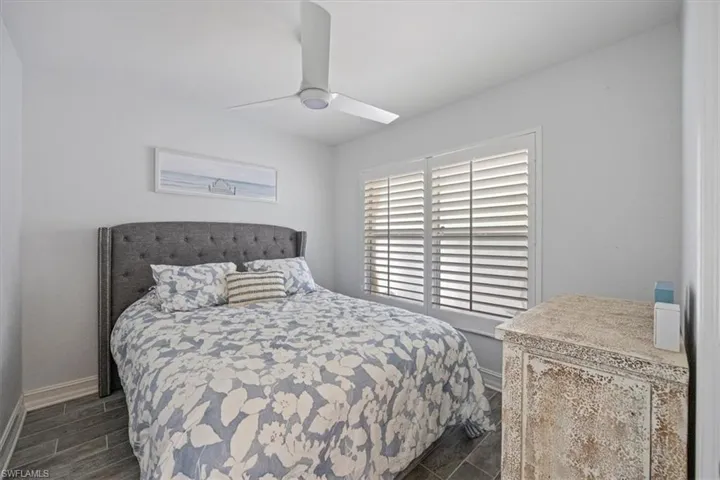 Bedroom featuring dark wood-style flooring, baseboards, and ceiling fan
