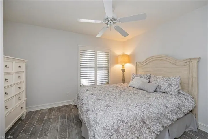 Bedroom featuring ceiling fan, baseboards, and dark wood-style flooring