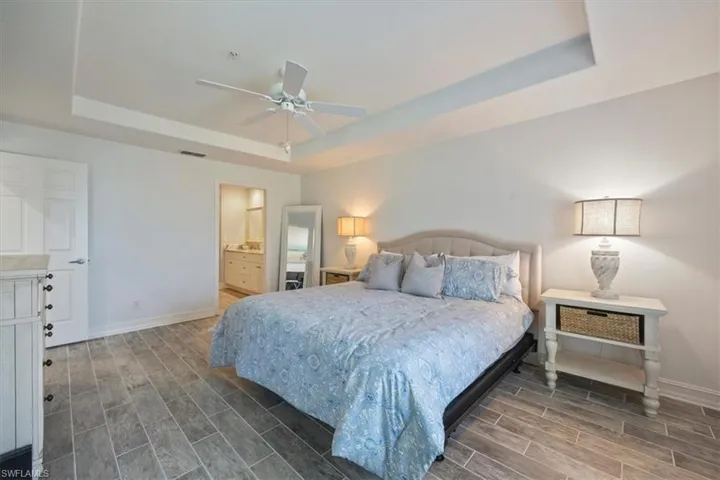 Bedroom with a tray ceiling, wood finish floors, and baseboards
