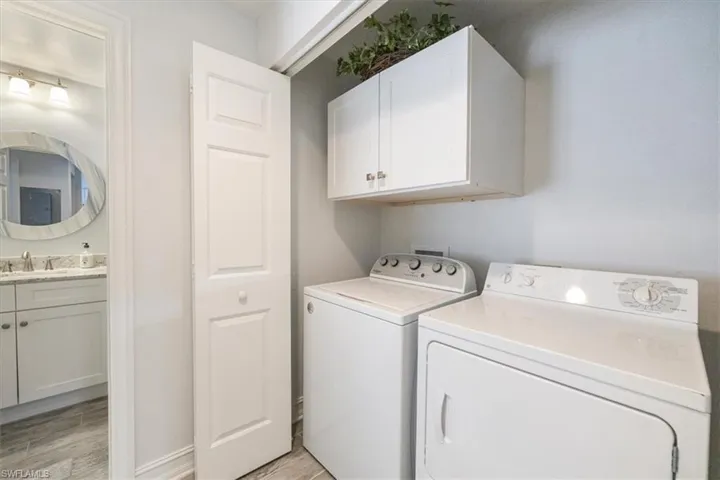 Laundry room featuring cabinet space, light wood-style flooring, washer and dryer, and a sink