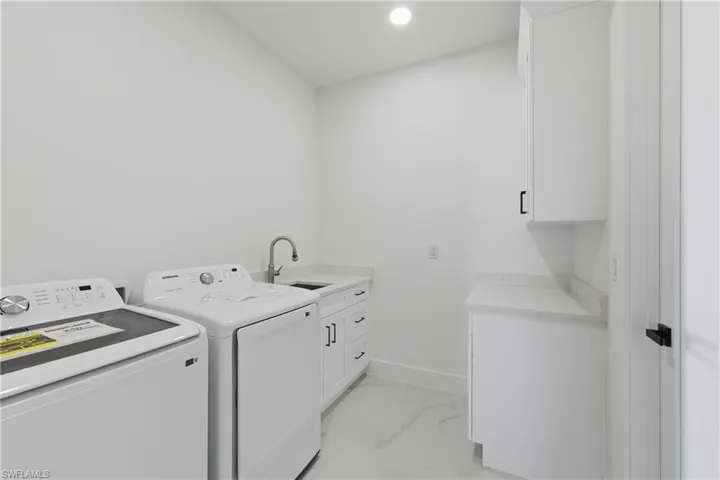 Laundry room with cabinet space, recessed lighting, washer and clothes dryer, and light marble finish floors