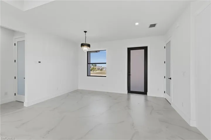 Empty room with a chandelier and recessed lighting