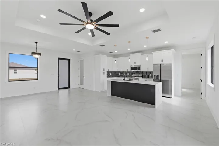 Kitchen with decorative light fixtures, open floor plan, stainless steel appliances, a raised ceiling, and recessed lighting