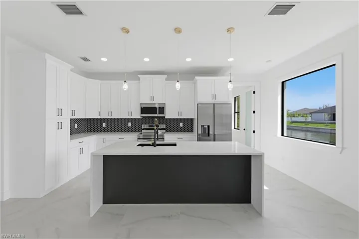 Kitchen with pendant lighting, stainless steel appliances, an island with sink, light stone countertops, and recessed lighting