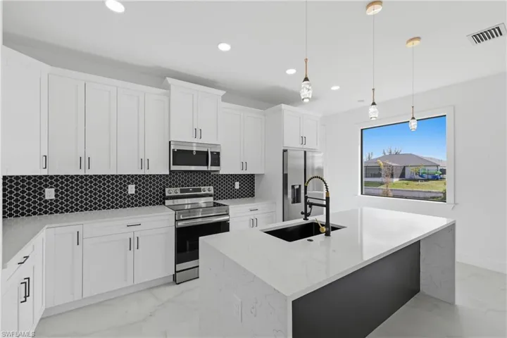 Kitchen featuring appliances with stainless steel finishes, hanging light fixtures, light stone counters, white cabinetry, and recessed lighting