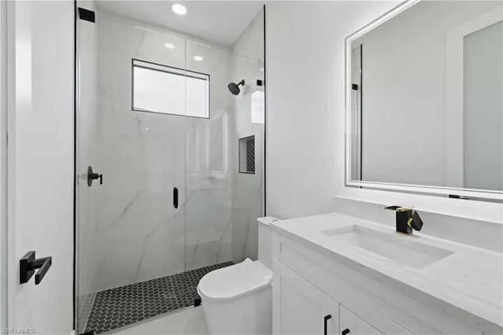 Full bathroom with a marble finish shower, vanity, and recessed lighting