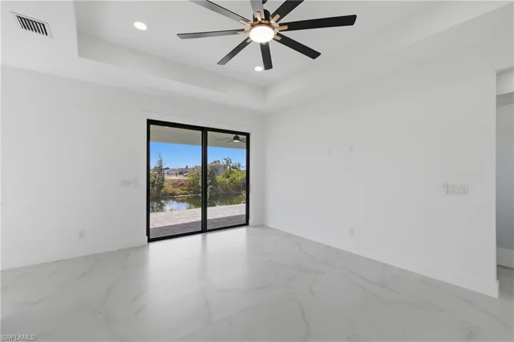 Spare room featuring a tray ceiling, a water view, recessed lighting, and marble finish floors