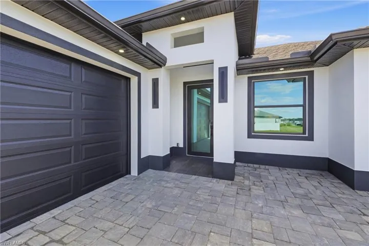 Doorway to property featuring stucco siding, a patio area, and driveway