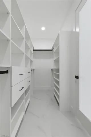 Walk in closet featuring light marble finish floors