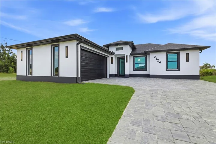 Prairie-style house with stucco siding, driveway, a front lawn, and a garage