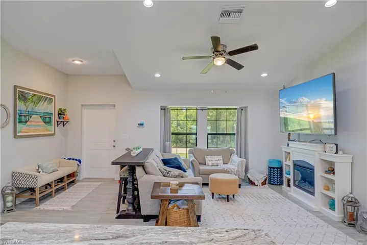Living area with recessed lighting, light wood finished floors, a ceiling fan, and a glass covered fireplace