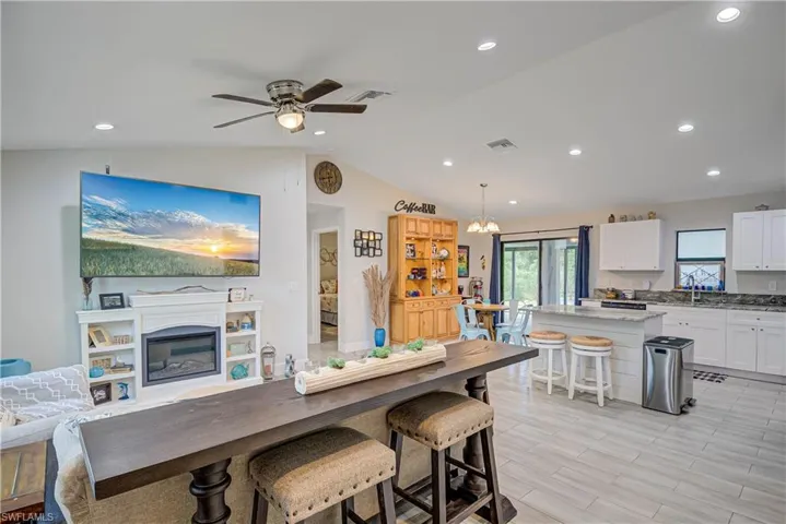Kitchen featuring a kitchen breakfast bar, white cabinets, light stone countertops, lofted ceiling, and pendant lighting
