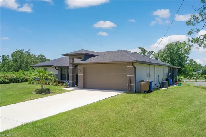 View of front of house with an attached garage, a front lawn, stucco siding, concrete driveway, and roof with shingles