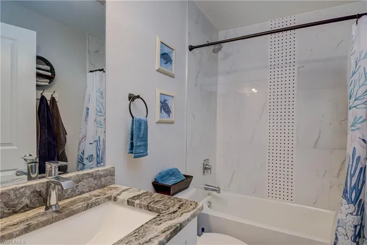 Full bathroom featuring shower / tub combo with curtain, vanity, and a textured wall