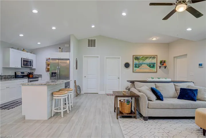 Living room with recessed lighting, lofted ceiling, light wood-type flooring, and a ceiling fan