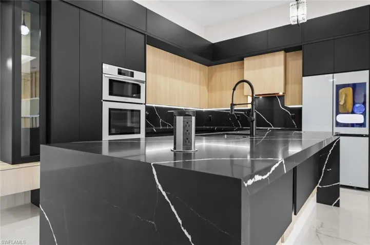 Kitchen featuring dark cabinetry, modern cabinets, and marble finish floor