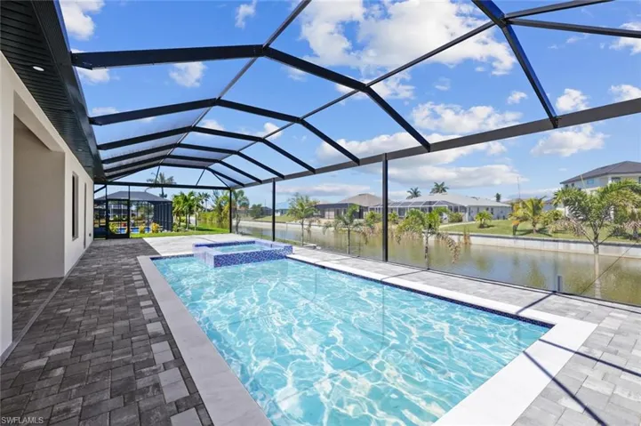 View of swimming pool featuring a patio, a pool with connected hot tub, a water view, a lanai, and a residential view