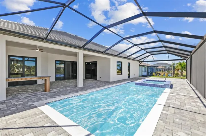 View of pool with a ceiling fan, glass enclosure, a patio area, and a pool with connected hot tub