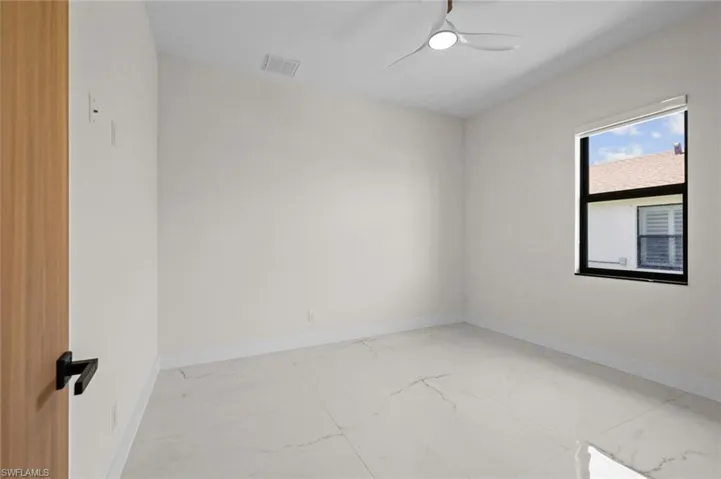 Empty room featuring visible vents, marble finish floor, a ceiling fan, and baseboards