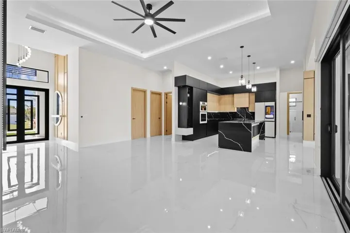 Kitchen featuring marble finish floor, modern cabinets, a ceiling fan, a tray ceiling, and a kitchen island