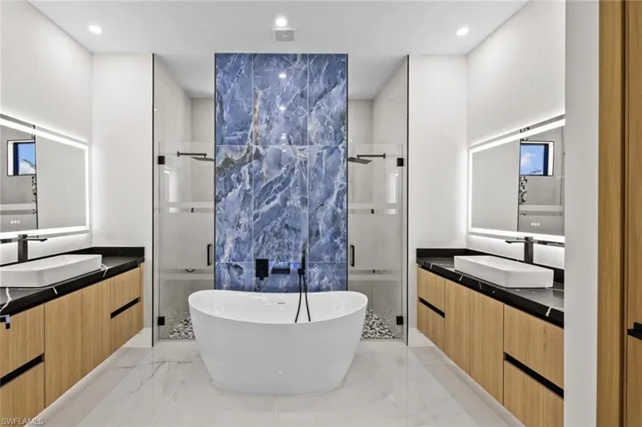 Full bath featuring a sink, two vanities, marble finish floor, and a stall shower