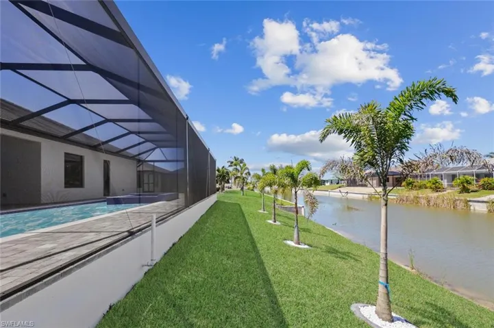 View of yard featuring glass enclosure, an outdoor pool, and a water view