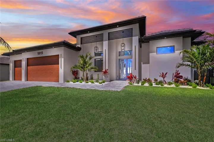 Contemporary home featuring stucco siding, an attached garage, driveway, and a front yard
