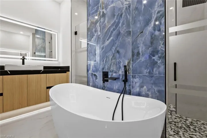 Bathroom featuring a soaking tub, marble finish floor, vanity, and a walk in shower