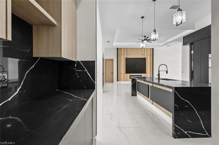 Kitchen with a raised ceiling, modern cabinets, marble finish floor, and a sink