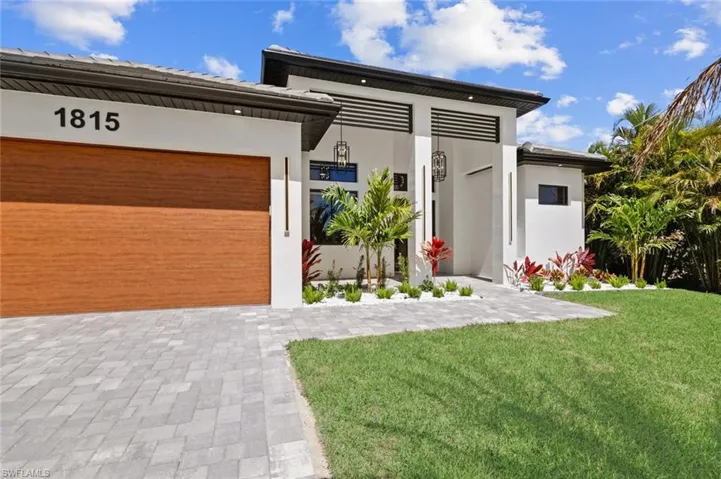 Contemporary home featuring stucco siding, driveway, a garage, and a front yard