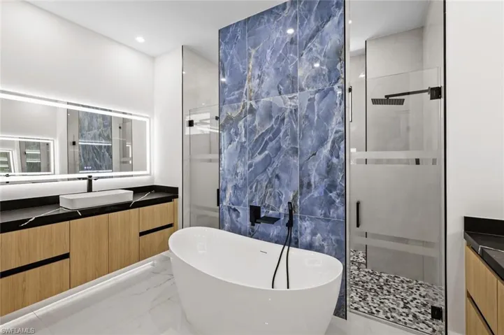 Full bath featuring a soaking tub, marble finish floor, vanity, and a shower stall