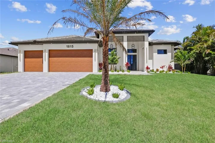 Prairie-style house with a front lawn, decorative driveway, an attached garage, and stucco siding
