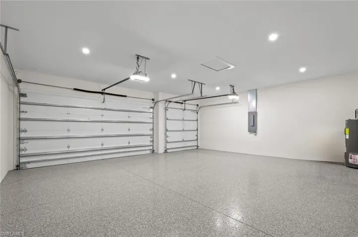Garage with electric panel, recessed lighting, water heater, and a garage door opener