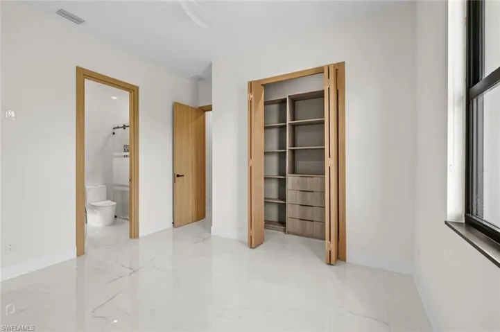 Unfurnished bedroom featuring visible vents, baseboards, marble finish floor, and ensuite bathroom
